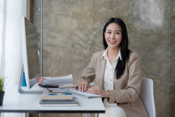 Charming Asian business woman have a happy of working laptop at the office. Looking at camera.