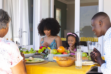 Multiracial multigeneration family praying before having lunch while sitting at dining table at home