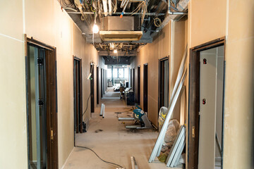 Unfinished interior, Uncovered ceiling with visible plumbing and wiring: Interior construction site of a new office building