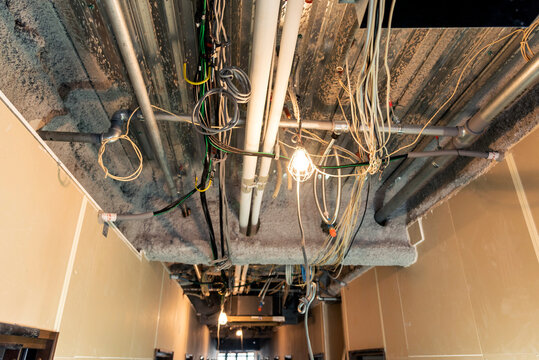 Unfinished interior, Uncovered ceiling with visible plumbing and wiring: Interior construction site of a new office building