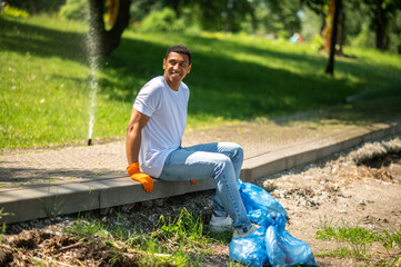 Obraz premium Dark-skinned man sitting in park smiling to side