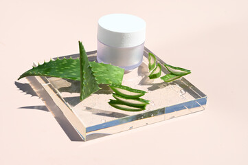 Styled beauty composition. Skin cream jar, aloe vera leaf on glass podium. Organic cosmetics, spa...