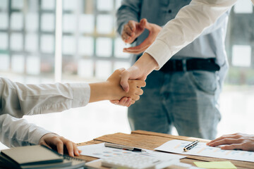 Business people shaking hands finishing up meeting or negotiation in sunny office. Business handshake and partnership concepts