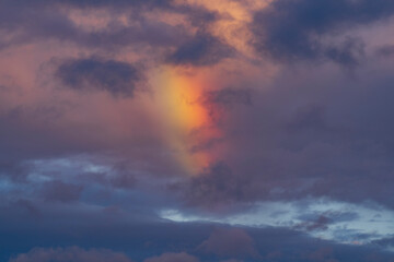 Fototapeta na wymiar Rainbow in dramatic clouds after rain in the evening sky.