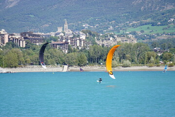 two kite surfers on serre ponçon lake alps france by embrun town on the cliff