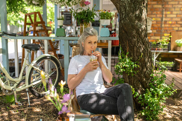 A mature woman sitting outside and drinking her cocktail