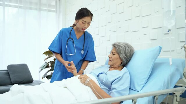 Female doctor doing physical therapy Have an elderly female patient lying in bed receiving saline in the patient room. Female doctor talking and encouraging elderly female patients.