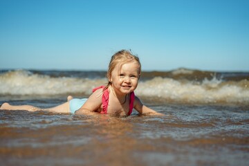 Little girl lying in sea in waves