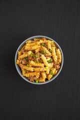 Homemade One-Pot Cheeseburger Pasta in a Bowl on a black background, top view. Flat lay, overhead, from above.