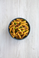 Homemade One-Pot Cheeseburger Pasta in a Bowl on a white wooden surface, top view. Flat lay, overhead, from above.