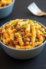 Homemade One-Pot Cheeseburger Pasta in a Bowl on a black background, low angle view.