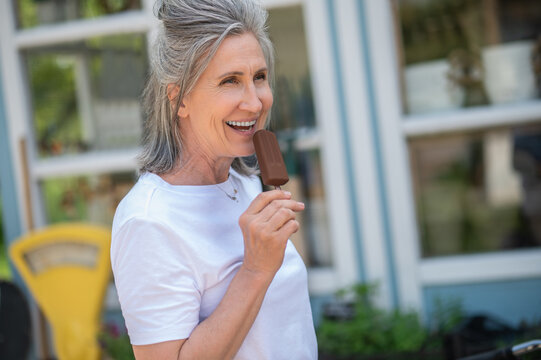 A Happy Mature Woman Eating Ice-cream And Looking Enjoyed