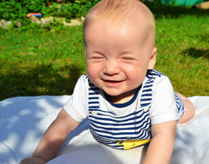 Happy baby squints his eyes from the sun