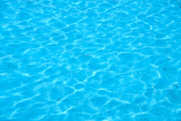 The wind makes the water ripple.  Blue swimming pool reflecting the sun rippled. Rubbish at the bottom of the pool, dirty blue bottom of the pool.