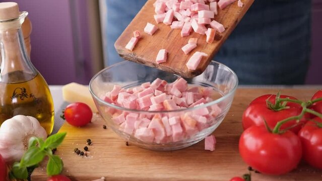 Making pasta carbonara - pouring pancetta bacon into glass bowl