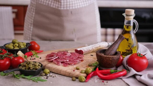 Sliced fuet sausage pieces falling onto wooden cutting board at domestic kitchen