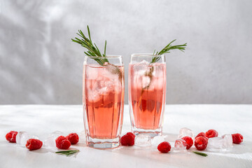 Summer refreshing non-alcoholic cocktails. Raspberry lemonade garnished with fresh rosemary. Summer raspberry beverage with sparkling water. Copy space.