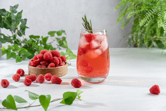 Summer refreshing non-alcoholic cocktails. Raspberry lemonade garnished with fresh rosemary. Summer raspberry beverage with sparkling water. Copy space.