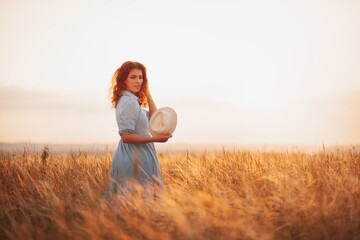 Woman in the field with flowers on sunset background