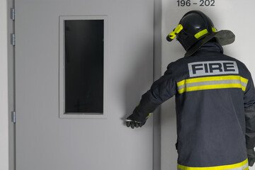 Fototapeta premium a fireman opens the front door in the entrance, rear view