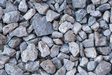 Textured surface of dirt road filled with large screenings of crushed stone.