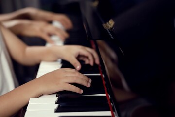 Obraz premium Choose to focus on the boy's fingers and the piano key teacher to play the piano. There are musical instruments for concerts or music lessons. Close-up of a child musician playing the piano