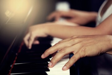 Select the focus on the piano trainer fingers and piano keys to play the piano. There are musical instruments for concerts or music lessons. Close-up of child musicians playing piano on stage