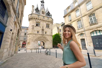 Fotobehang Beautiful tourist girl visiting the city of Bordeaux, France. Attractive woman looking at camera with Porte Cailhau fortified gateway in Bordeaux, France. © zigres