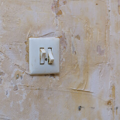 Old light switch on a shabby battered wall. Selective focus