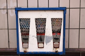 Alter blau-weißer Kaugummiautomat an weißer Kachelwand 