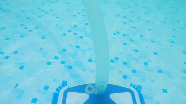 Close-up vacuum cleaner-brush with plastic tubes cleans the bottom of the pool. The concept of cleaning a pool at home. Shooting underwater