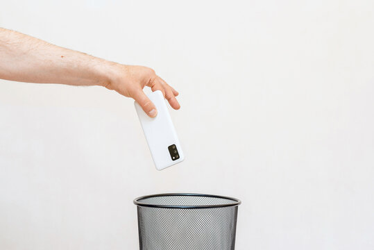 The smartphone is thrown into the trash for disposal and recycling.White,gray background,selective focus,copy space.