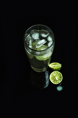 Glass of cold lemonade on black table. Ice cold drink on dark background.