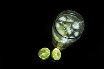 Glass of cold lemonade on black table. Ice cold drink on dark background.