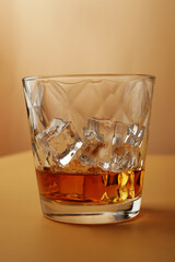 crystal glass with ice and whiskey with reflection on dark background seen in a swooping view