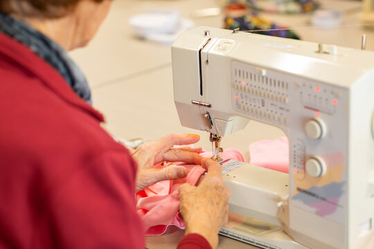 elderly lady sewing hem on garment with sewing machine