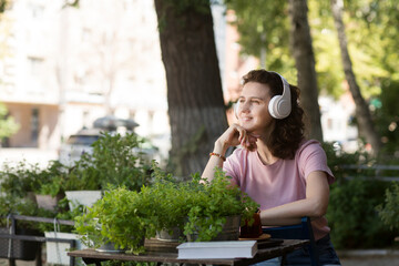 middle aged woman wearing headphones relaxed in the garden near the house in summer. concept without stress. mental health. Slow life. Enjoying the little things. 