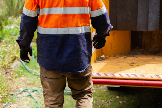 Tradie feeding branches into wood chipping machine