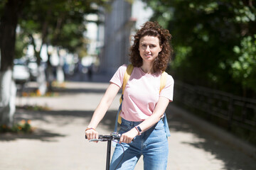 middle aged woman with a backpack rides a scooter around the city on a summer day