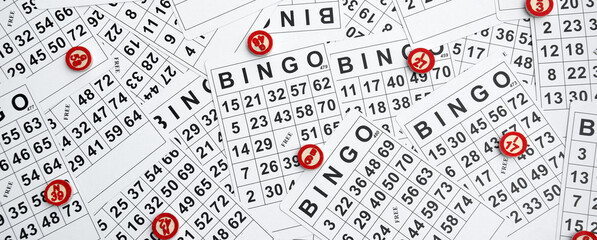 Many wooden chips with numbers and cards for a board game of bingo or lotto on a light background.