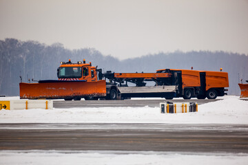 Snowplow truck cleans runway on airfield during snowfall