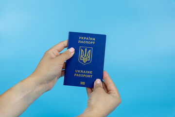 Passport of a citizen of Ukraine in female hands on a blue background close-up. Inscription in Ukrainian Passport of Ukraine