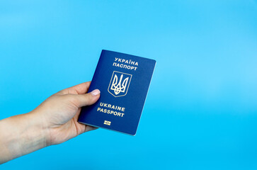 Biometric Ukrainian passport on a blue background in a female hand. Passport of a citizen of Ukraine