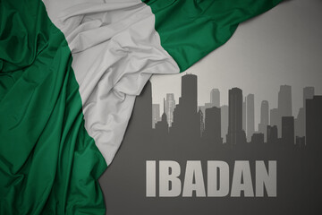 abstract silhouette of the city with text Ibadan near waving colorful national flag of nigeria on a...
