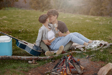 Happy young couple hugging and kissing at fire at nature. Romantic day and traveling. 