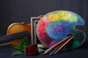 Artistic palette with brushes, violin and red rose.