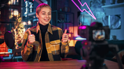 Confident Young Female Talking Into Microphone While Recording Radio Show from Her Loft Apartment. Happy Woman with Short Hair Talking on Camera and Recording Podcast Live on Social Media.