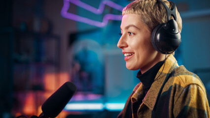 Attractive Young Female Talking Into Microphone While Recording Radio Show from Her Loft Apartment. Happy Woman with Short Hair Talking on Camera and Recording Podcast Live on Social Media.