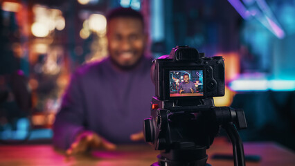 Handsome Young African American Man Talking Into Microphone While Recording Radio Show from His Loft Apartment. Happy Black Male Talking on Camera and Recording Podcast Live on Social Media.