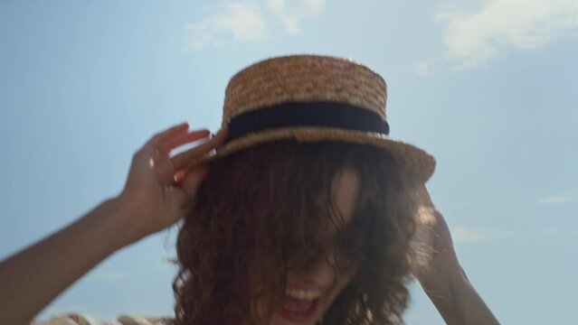 Excited woman jumping holding straw hat on head closeup. Lady having fun.